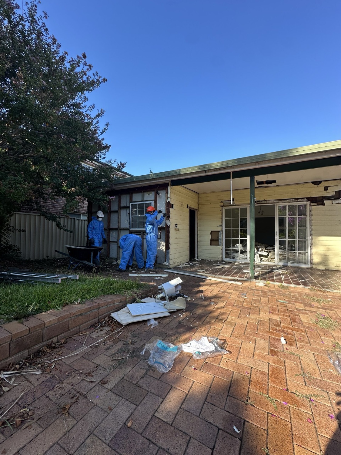 Licensed asbestos removalists in full protective suits working at a Sydney home